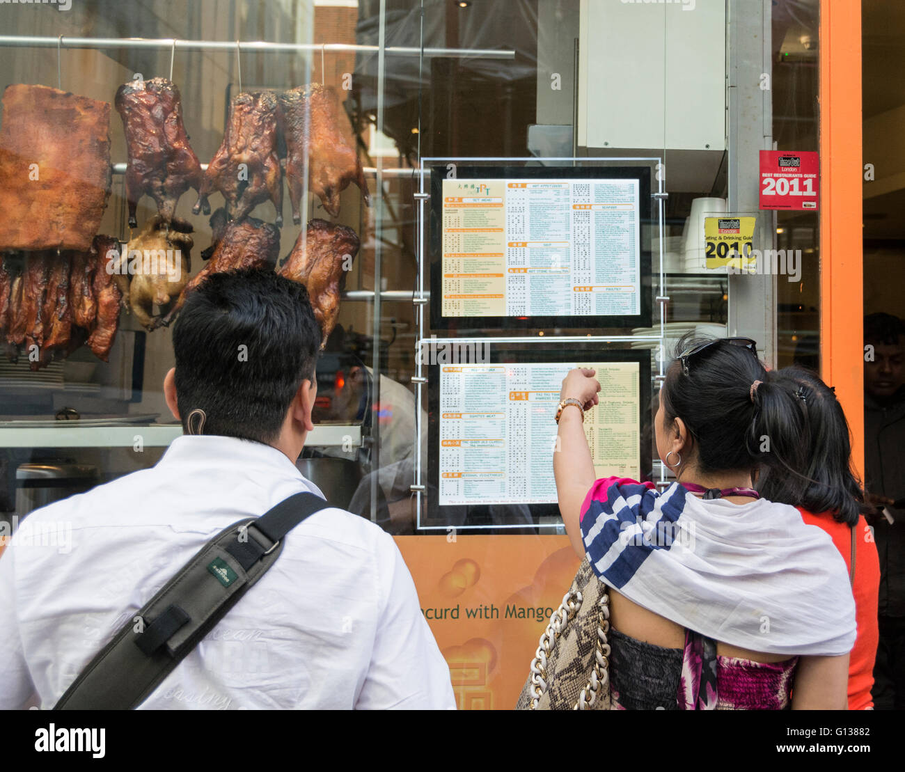 Fenster-Käufer wählen ihre chinesischen Abendessen in Londons Chinatown Bereich Stockfoto