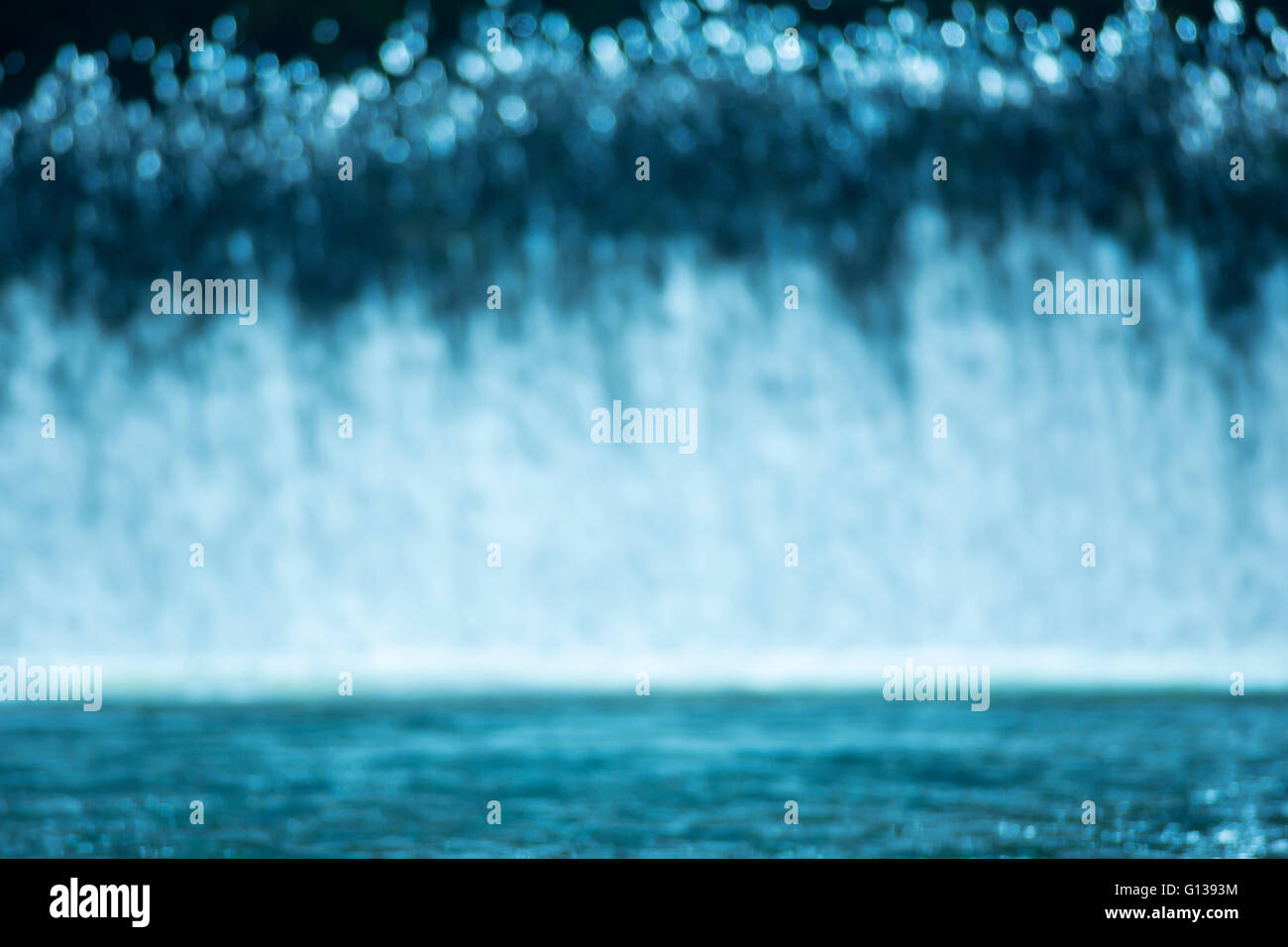 VORHANG VON FRISCHEM WASSER-KASKADEN ÜBER HOCHWASSERENTLASTUNG IN RUHIGEN POOL AM FLÜSSCHEN Stockfoto