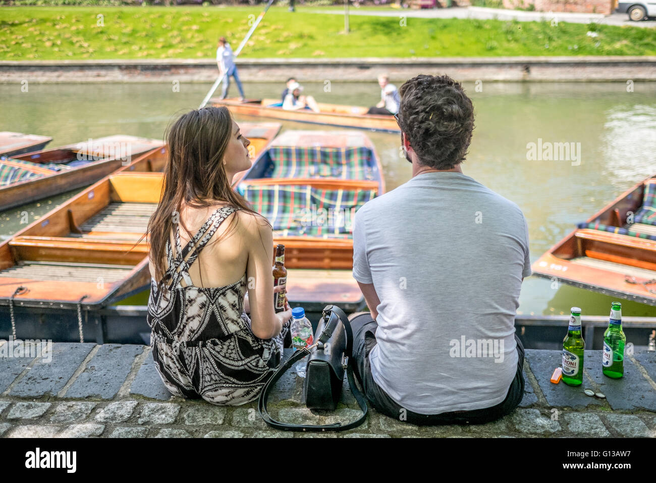 Ein schönes Paar sitzt am Ufer des Flusses Cam in der Nähe von Kai Pier an einem warmen und sonnigen Tag im Mai.  Cambridge punt Stechkahn fahren Stockfoto
