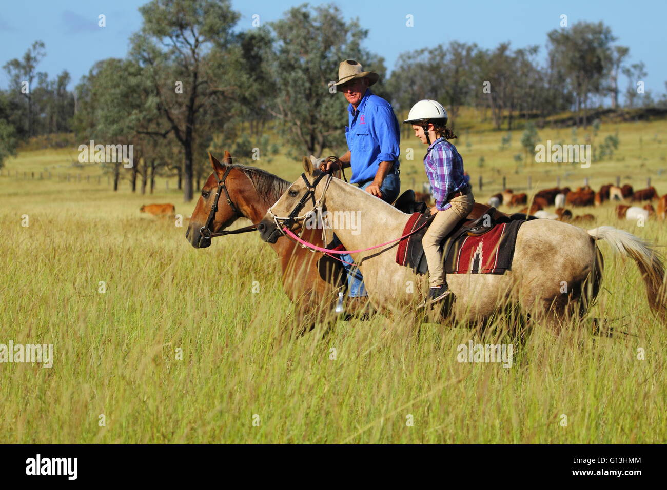 Ein Großvater und junge Enkelin Reitpferde auf einem Vieh-Grundstück in der Nähe von Eidsvold in Queensland, Australien. Stockfoto