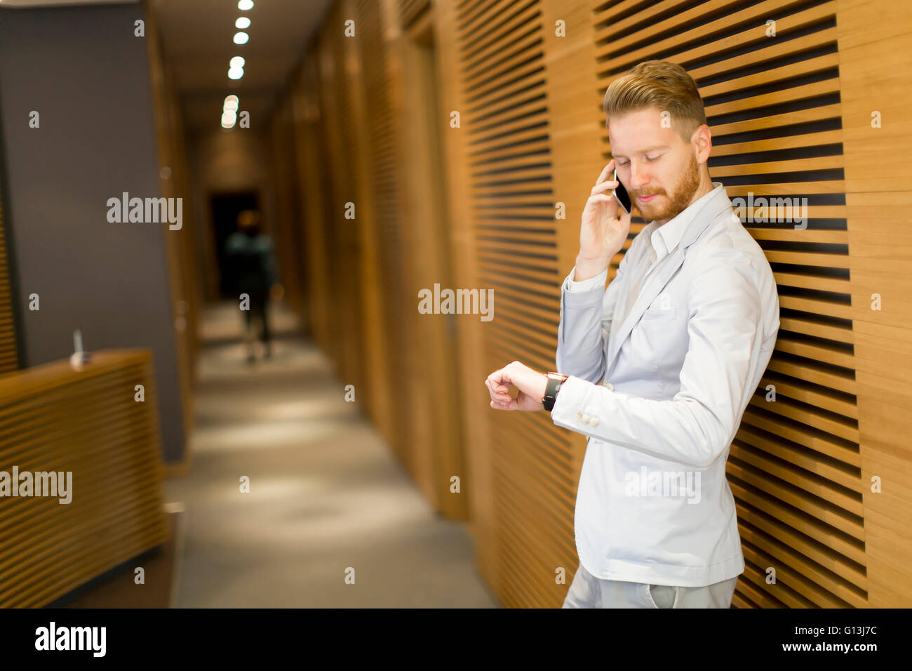 Junge rothaarige Mann mit Handy im Büro Stockfoto