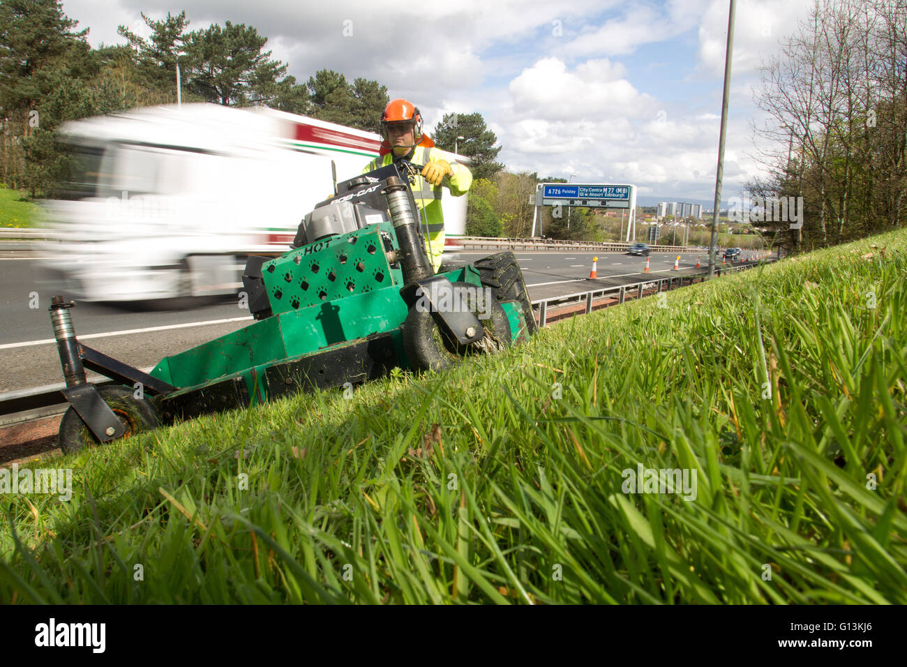 Rasen schneiden von stark frequentierten Autobahn M77 Stockfoto