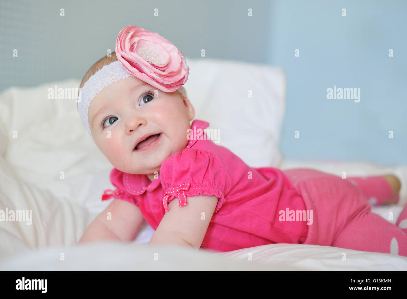 Süße kleine Baby erstaunt mit Pausbacken tragen rosa Kleidung und Band Blume Stockfoto