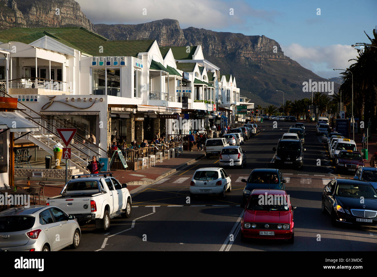 Straßenszene in der Victoria Road, Camps Bay Beach, mit Tafelbergen im Hintergrund Stockfoto