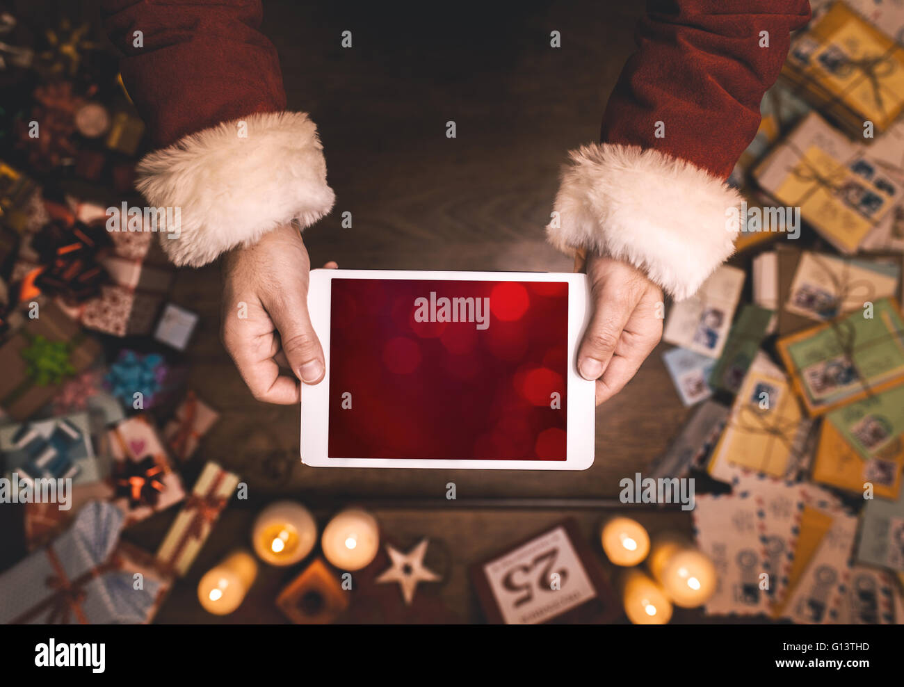 Santa Claus mit digital Touch-Screen-Tablette, Hände nah oben, Ansicht von oben, Desktop mit Buchstaben und Weihnachtsgeschenke Stockfoto