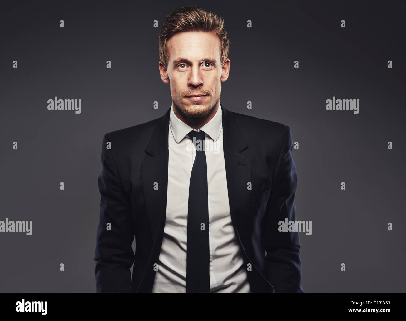 Porträt der schönen Business-Mann im dunklen Anzug vor einem grauen Hintergrund Stockfoto