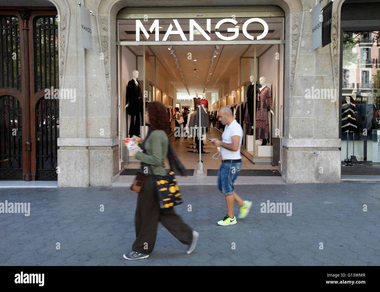 Leute gehen vorbei an einem Mango Shop / store in Passeig de Gracia, Barcelona, Spanien Stockfoto