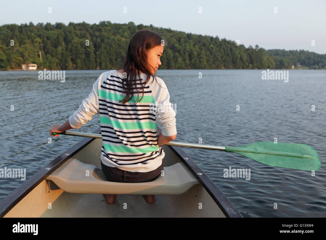 Junges Mädchen paddeln Kanu auf einem ruhigen See in westlichen Vermont im Sommer Stockfoto