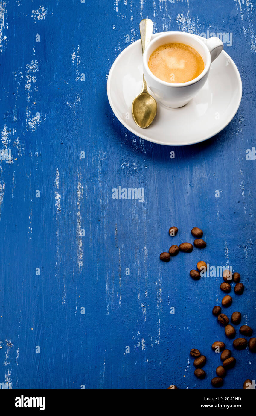Tasse Espressokaffee und Bohnen auf blau lackierten Holztisch Hintergrund. Draufsicht, vertikale Stockfoto