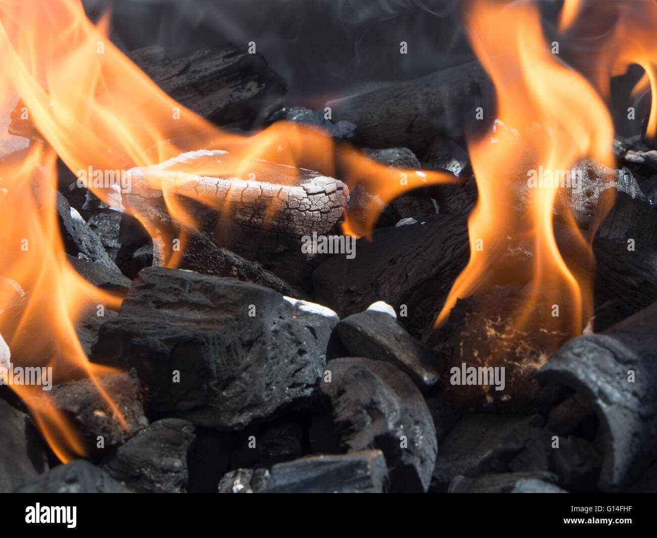 brennende Holzkohle mit Flammen auf einem Grill Stockfoto