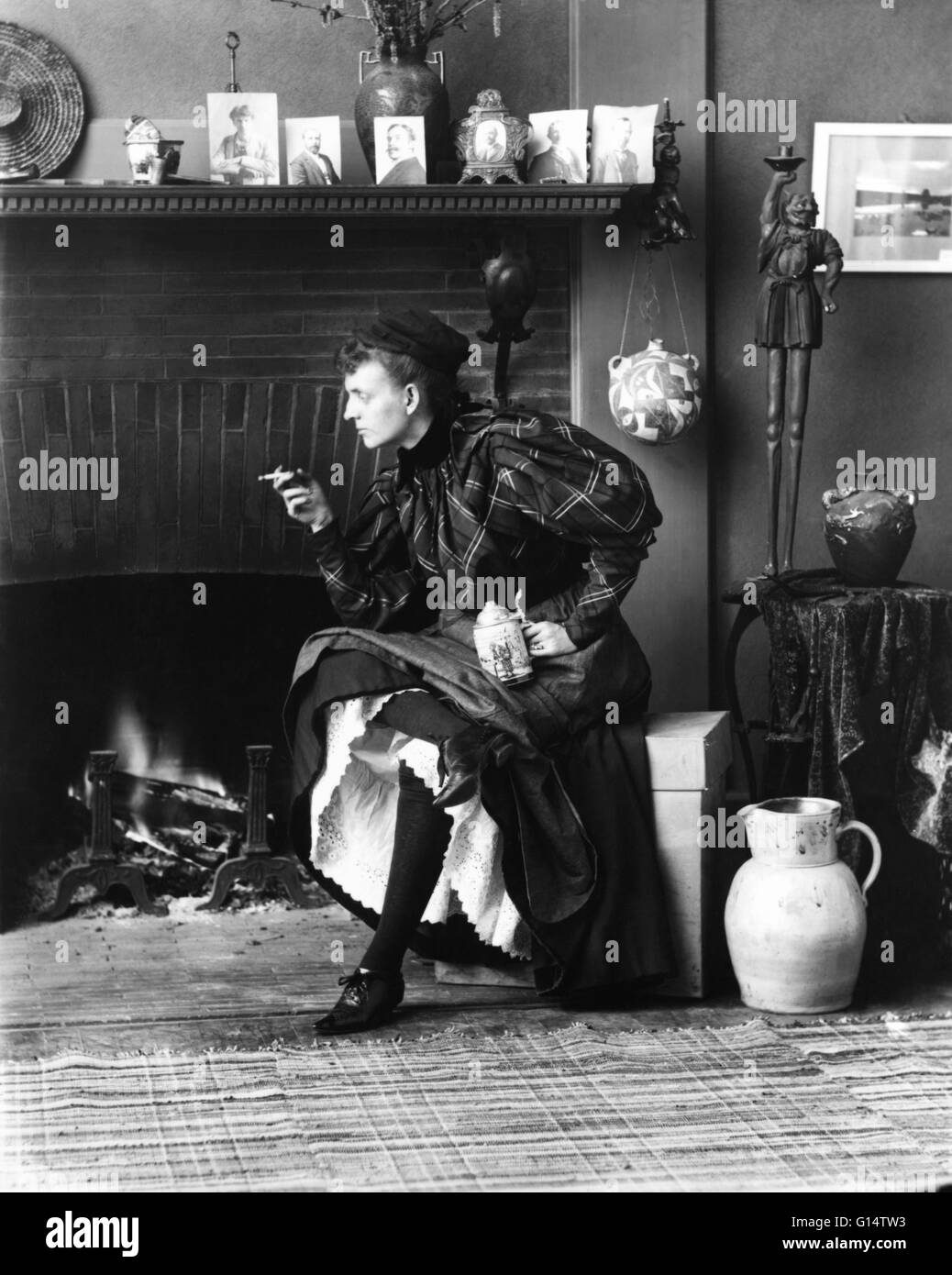 Johnston, sitzen vor dem Kamin, mit Blick auf Links, halten Zigarette in der einen Hand und ein Bierkrug in der anderen, in ihrem Studio Washington, D.C., 1896. "Fannie" Frances Benjamin Johnston (15. Januar 1864 - 16. Mai 1952) war einer der frühesten American f Stockfoto
