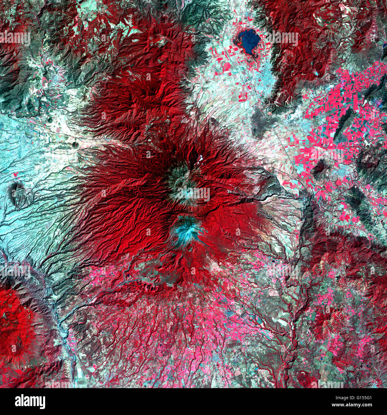 Colima Vulkan, Mexiko, Satellitenbild. Norden ist oben. Vegetation ist rot, unfruchtbare Gebieten sind hell blau, und Wasser ist dunkelblau. Der Vulkan (Mitte) hat zwei schneebedeckte Gipfel (blau). Die nördlichen, Nevado de Colima (4330 m), ist älter und inaktiv Stockfoto