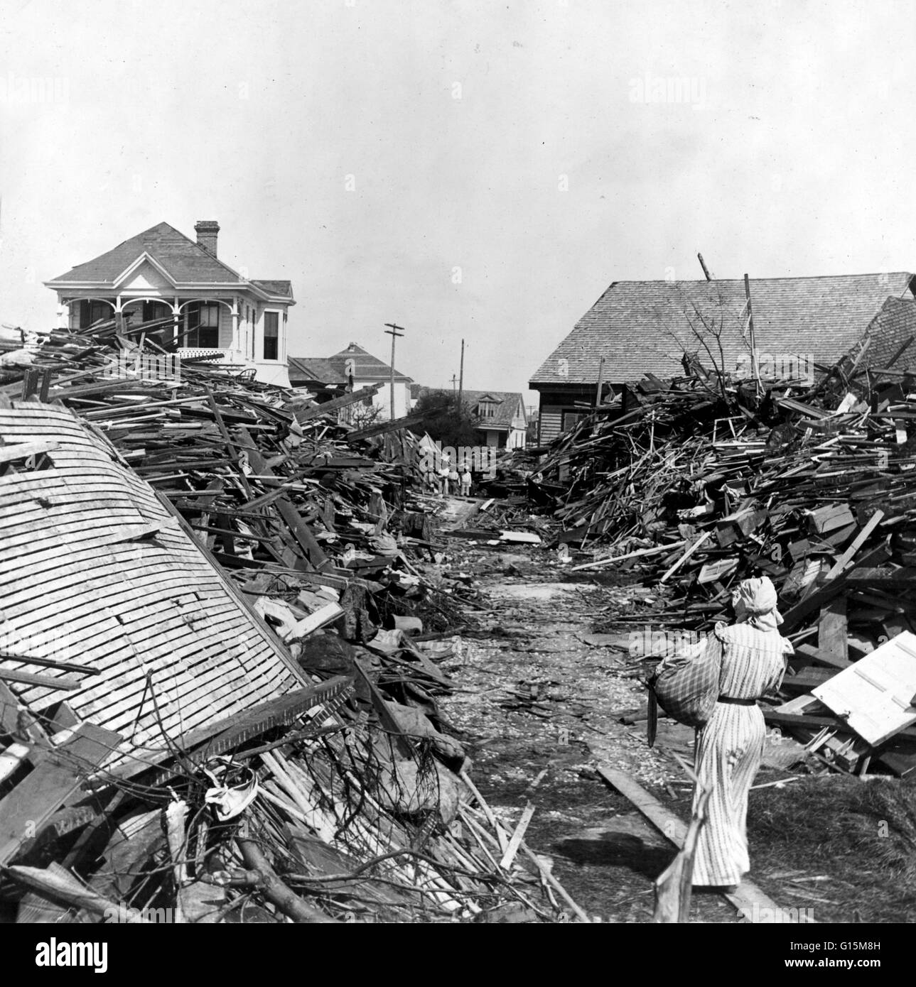 Eine Frau geht durch einen geöffneten Gang in den Trümmern, North auf 19. Street, Galveston, Texas den Hurrikan von 1900 machte Landfall auf der Stadt Galveston, Texas, am 8. September 1900. Es hatte Winde von 145 Meilen pro Stunde am Landfall, so dass es geschätzt. Stockfoto