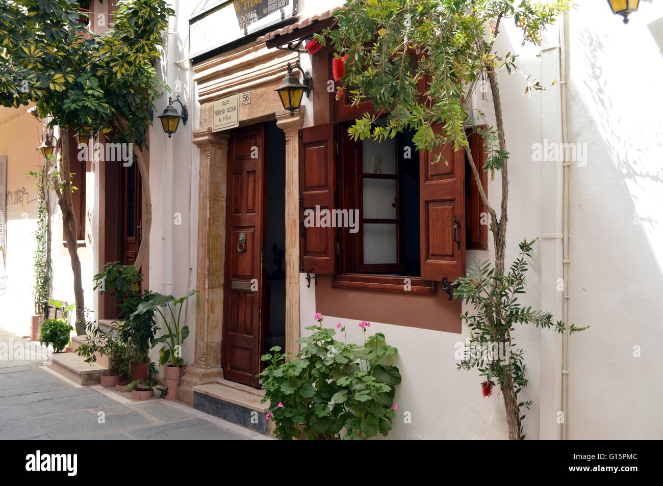 Weiße Fassade mit Fenster und Türen aus Holz mit grünen Bäumen. Stockfoto