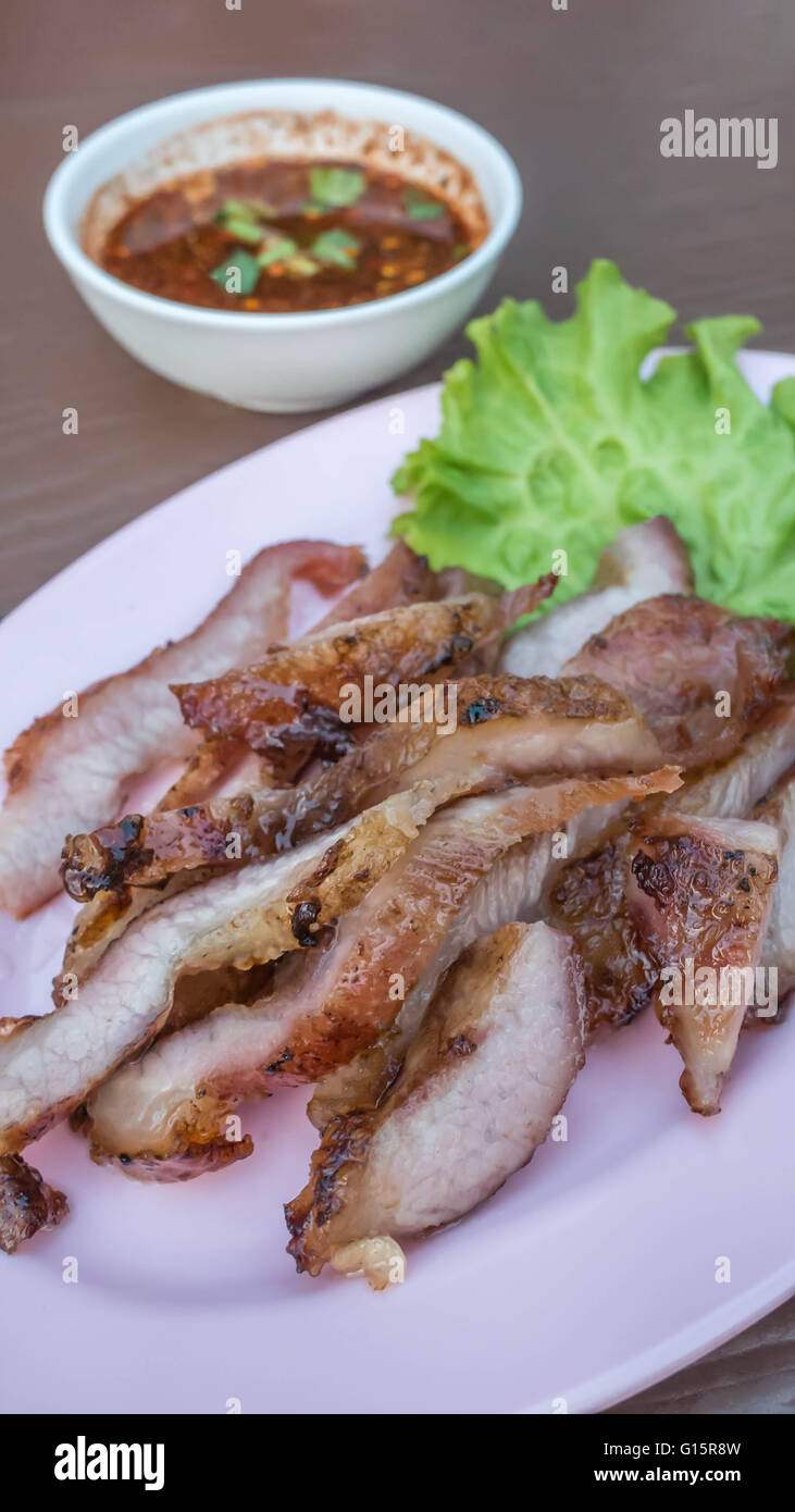 Gegrilltes Rindersteak mit grünen Blättern Salat geschnitten, auf rosa Teller serviert mit Chili-sauce Stockfoto