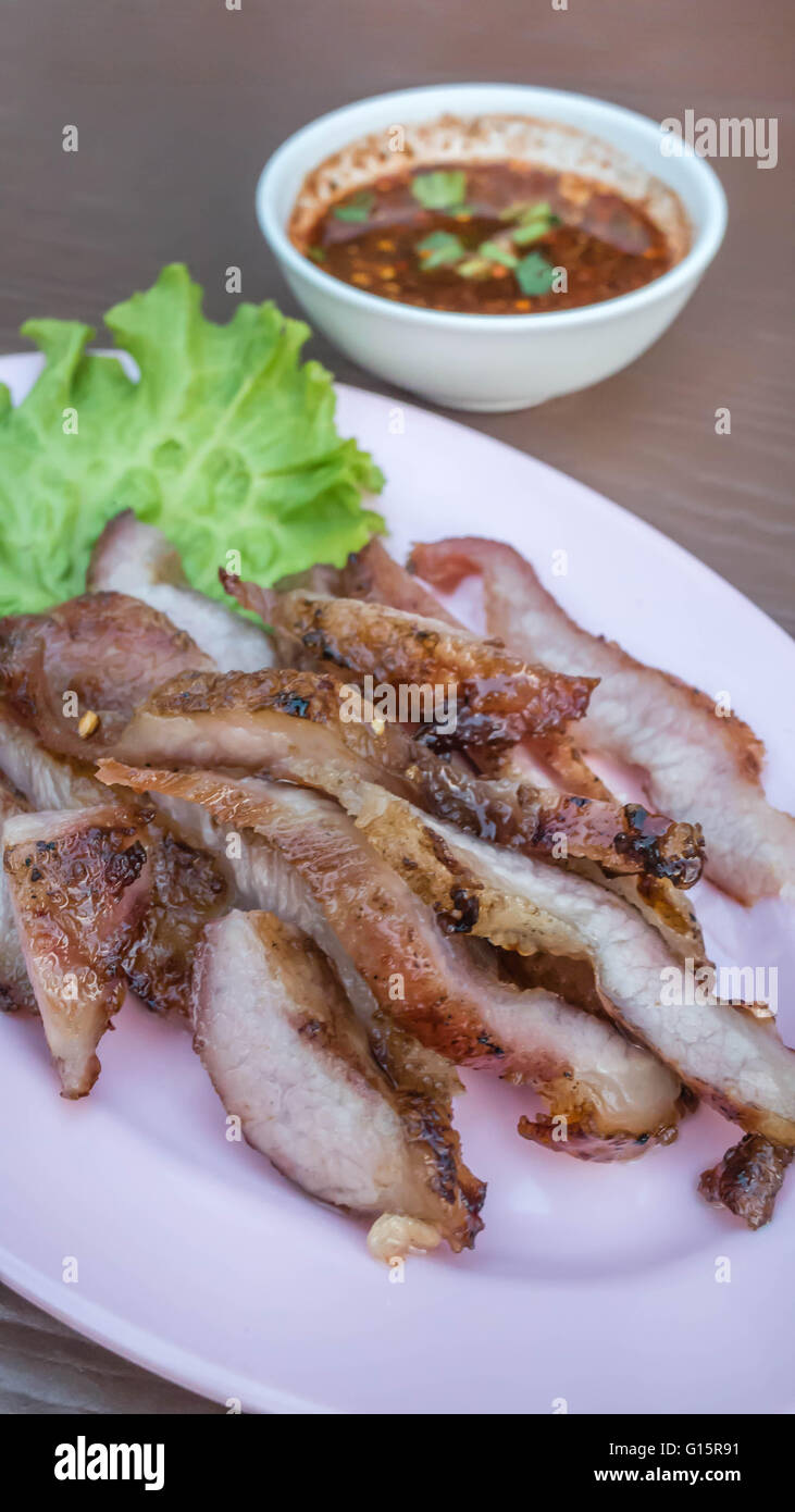 Gegrilltes Rindersteak mit grünen Blättern Salat geschnitten, auf rosa Teller serviert mit Chili-sauce Stockfoto