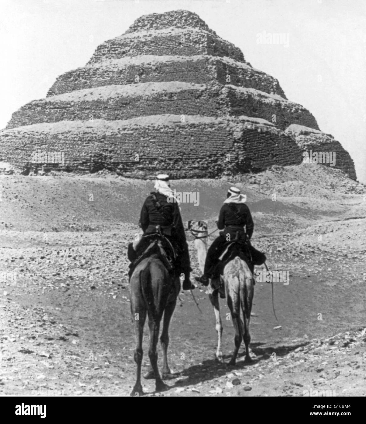 Unter dem Titel: "nubischen Soldaten Reiten Kamel Pass der Stufenpyramide, libysche Wüste, Ägypten". Die Pyramide des Djoser (oder Zoser) oder Stufenpyramide (Kbhw-Ntrw auf ägyptisch) ist eine archäologische bleiben in der Nekropole von Sakkara, Ägypten, nordwestlich von der Stadt Memphis. Stockfoto