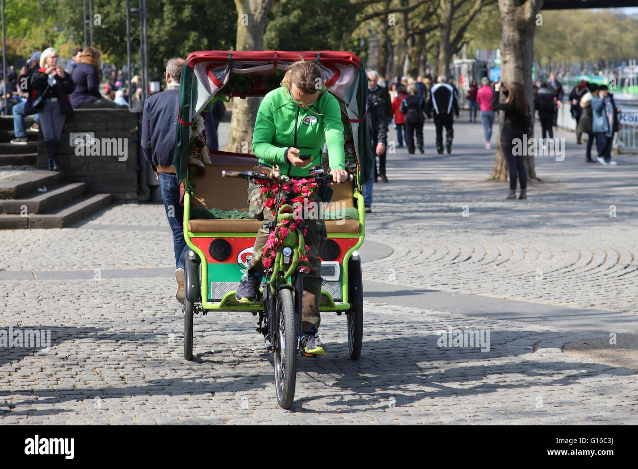 Riksha-Fahrerin, die auf der Suche auf Handy, Köln, NRW, Nordrhein Westfalen, Deutschland Stockfoto