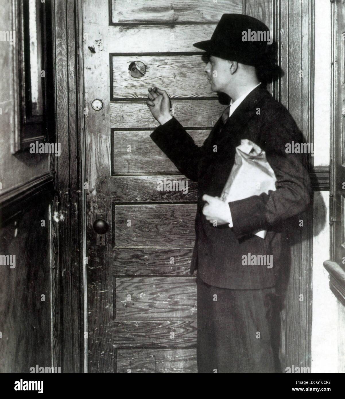 Ein Mäzen klopft an die Tür von einem Speakeasy. Hinweis Guckloch in der Tür. Ein Guckloch ermöglichte es den Menschen in die Sicherheit von außen ohne Öffnen der Tür zu sehen. POHO waren zahlreich und während der Prohibition Jahre populär. Einige von ihnen wurden betrieben Stockfoto