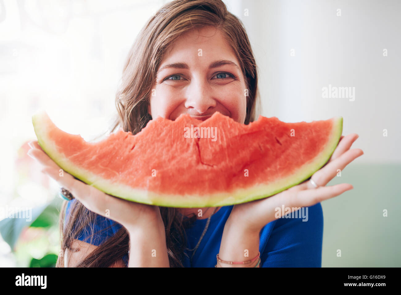 Porträt der glückliche junge Frau hält ein Stück Wassermelone vor ihr Gesicht. Stockfoto