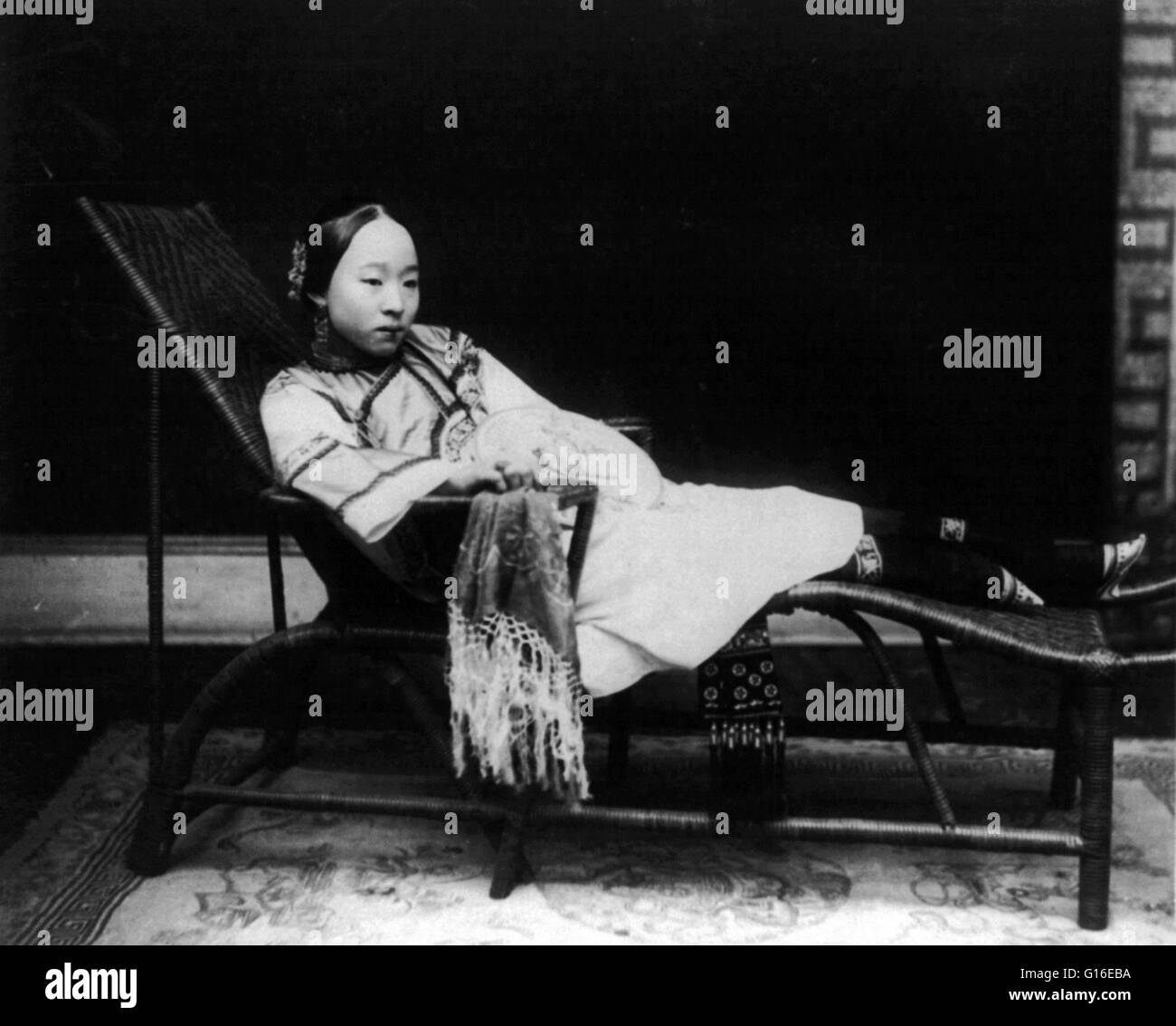 Unter dem Titel: "Frau mit gebundenen Füßen liegend auf Chaise Lounge, China. Ca. 1890 und 1923. Fußbindens (auch bekannt als "Lotus Feet") war der Brauch der Anwendung schmerzhaft enge Bindung zu den Füßen des jungen Mädchen um weiteres Wachstum zu verhindern. Die Praxis möglich Stockfoto