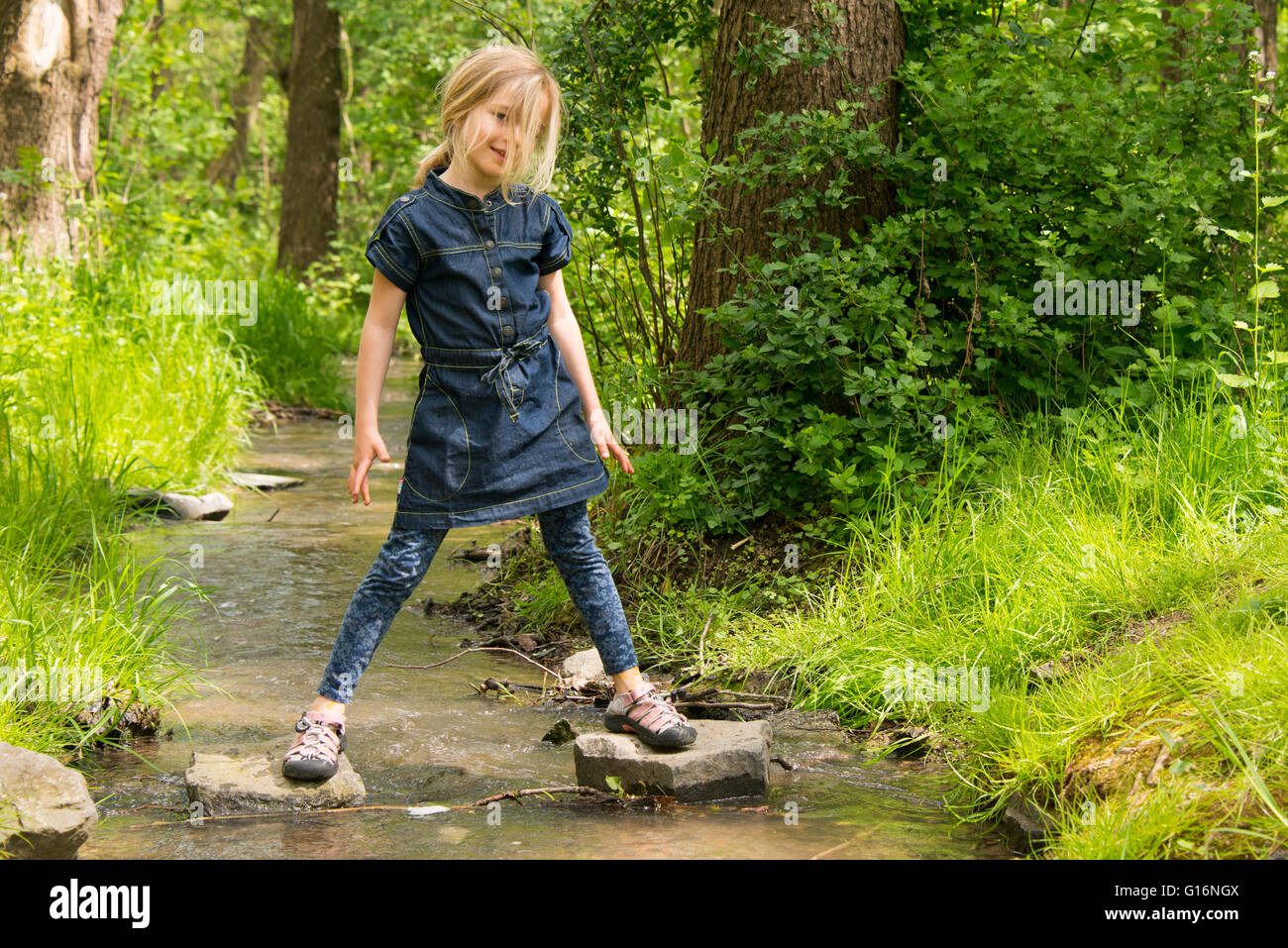 Niedliche kleine Mädchen, die Spaß an einem Fluss an warmen und sonnigen Sommertag Stockfoto