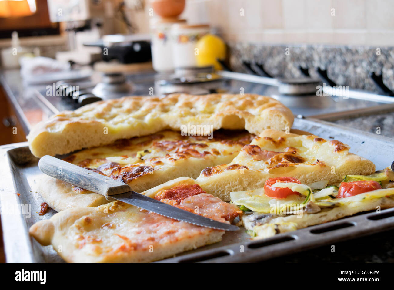Sortiment von Papierschnipseln Pizza auf einem Backblech auf einem Kochfeld Stockfoto