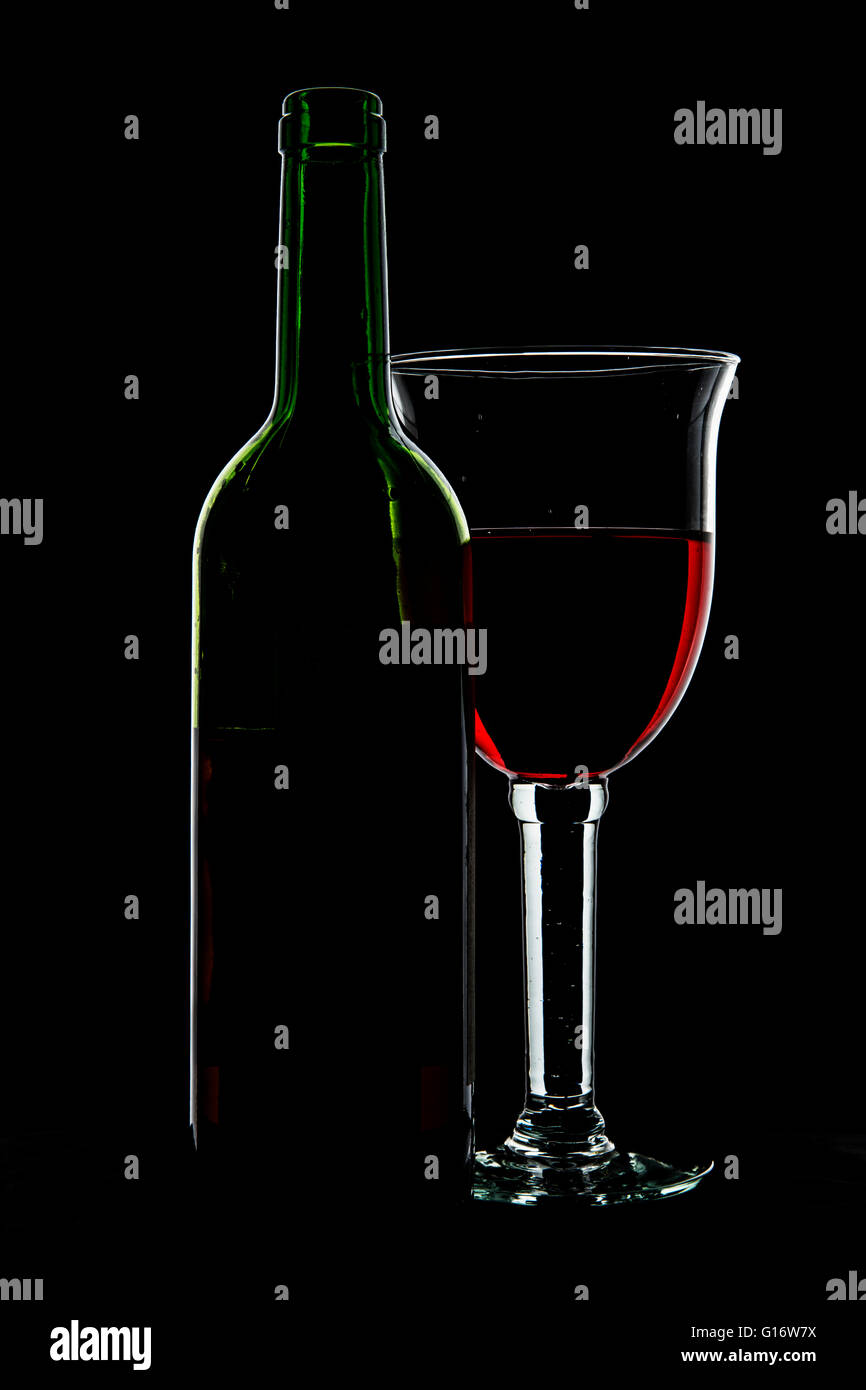 Glas Wein und eine Flasche bei schwachem Licht. Stockfoto