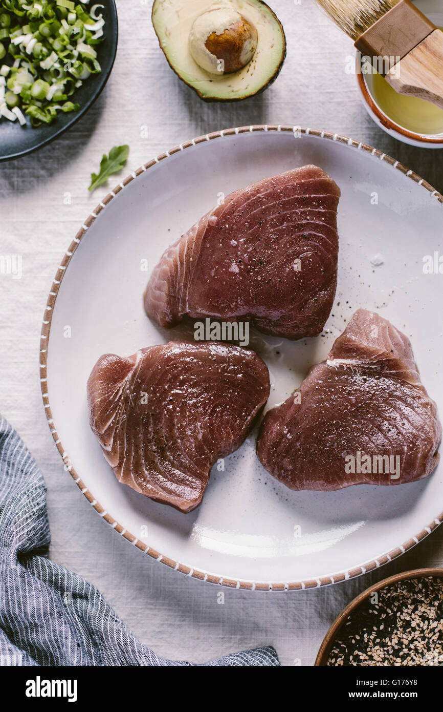 3 Stück frischer Yellow Fin Thunfisch mit Olivenöl bestrichen und mit Salz und Pfeffer gewürzt und aus Draufsicht fotografiert. Stockfoto