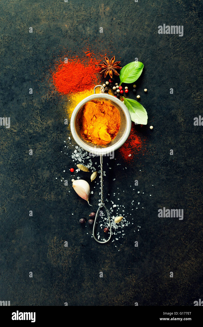 Kräuter und Gewürze-Auswahl (Kurkuma, Paprika, Basilikum, Salz, Papper) auf dunklem Hintergrund rustikal Stockfoto