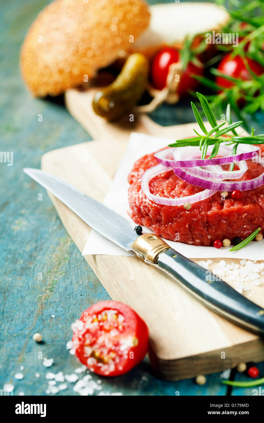 Rohes Rindfleischburger für Hamburger mit Gemüse auf Holztisch Stockfoto