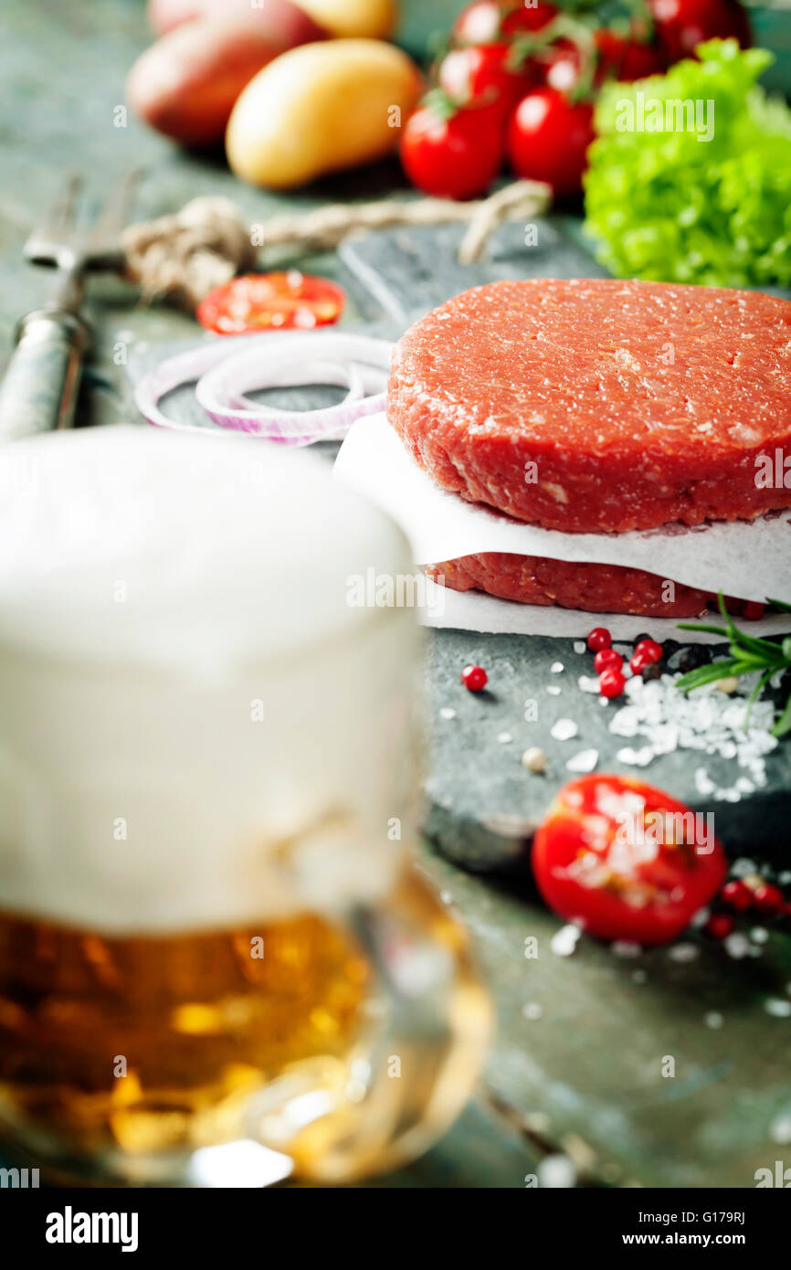 Rohen Boden Rindfleisch Fleisch Burger Steak Schnitzel mit Gewürzen, Gemüse und Bier auf Vintage Holzbrettern Stockfoto