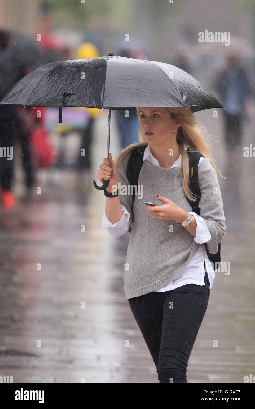 Eine Frau trägt einen Regenschirm bei starkem Regen. Stockfoto