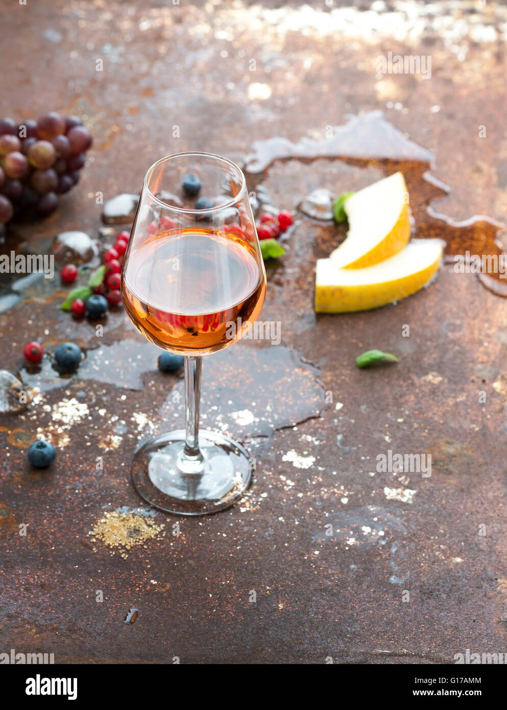 Glas Rosé mit Beeren, Melone, Trauben und Eis auf rostigen Metall Hintergrund Stockfoto