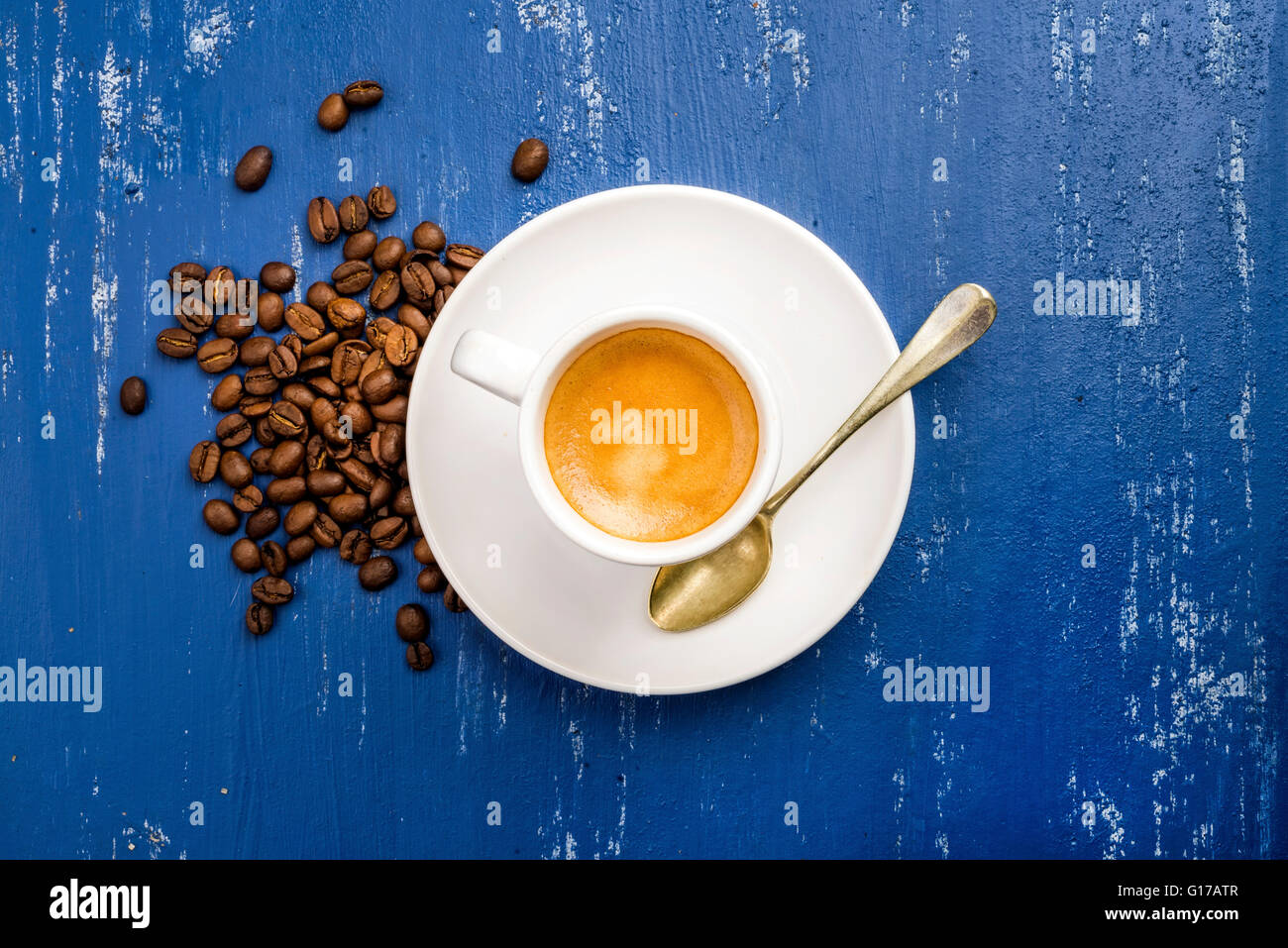 Tasse Espressokaffee und Bohnen auf blau lackierten Holztisch Hintergrund. Draufsicht, vertikale Stockfoto