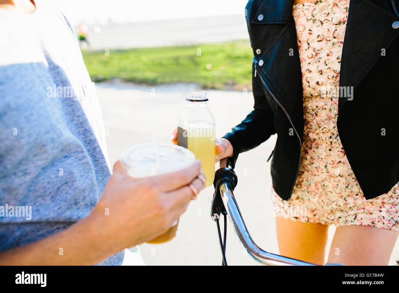 Zugeschnittene Aufnahme des jungen Paares mit Saft und Kaffee Getränke an Küste Stockfoto