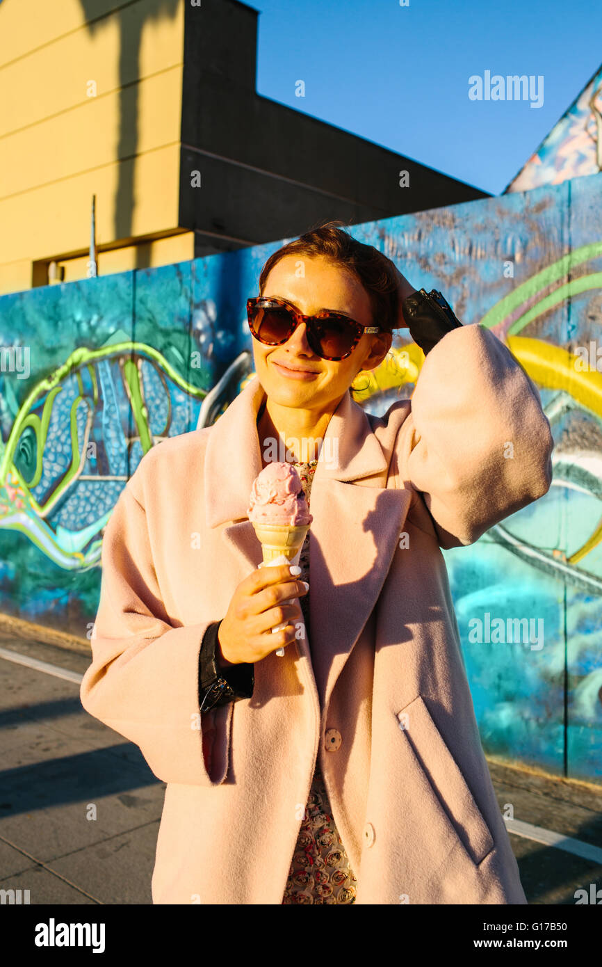 Porträt des jungen stilvolle Frau essen Eiscreme-Kegel vor Graffitiwand, Venice Beach, Kalifornien, USA Stockfoto