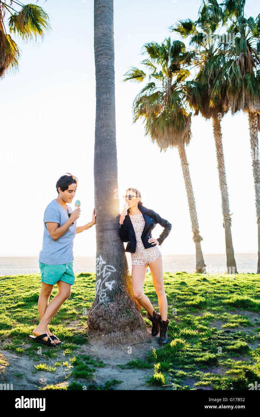 Junges Paar gelehnt sonnenbeschienenen Palme essen Eiscreme-Kegel, Venice Beach, Kalifornien, USA Stockfoto