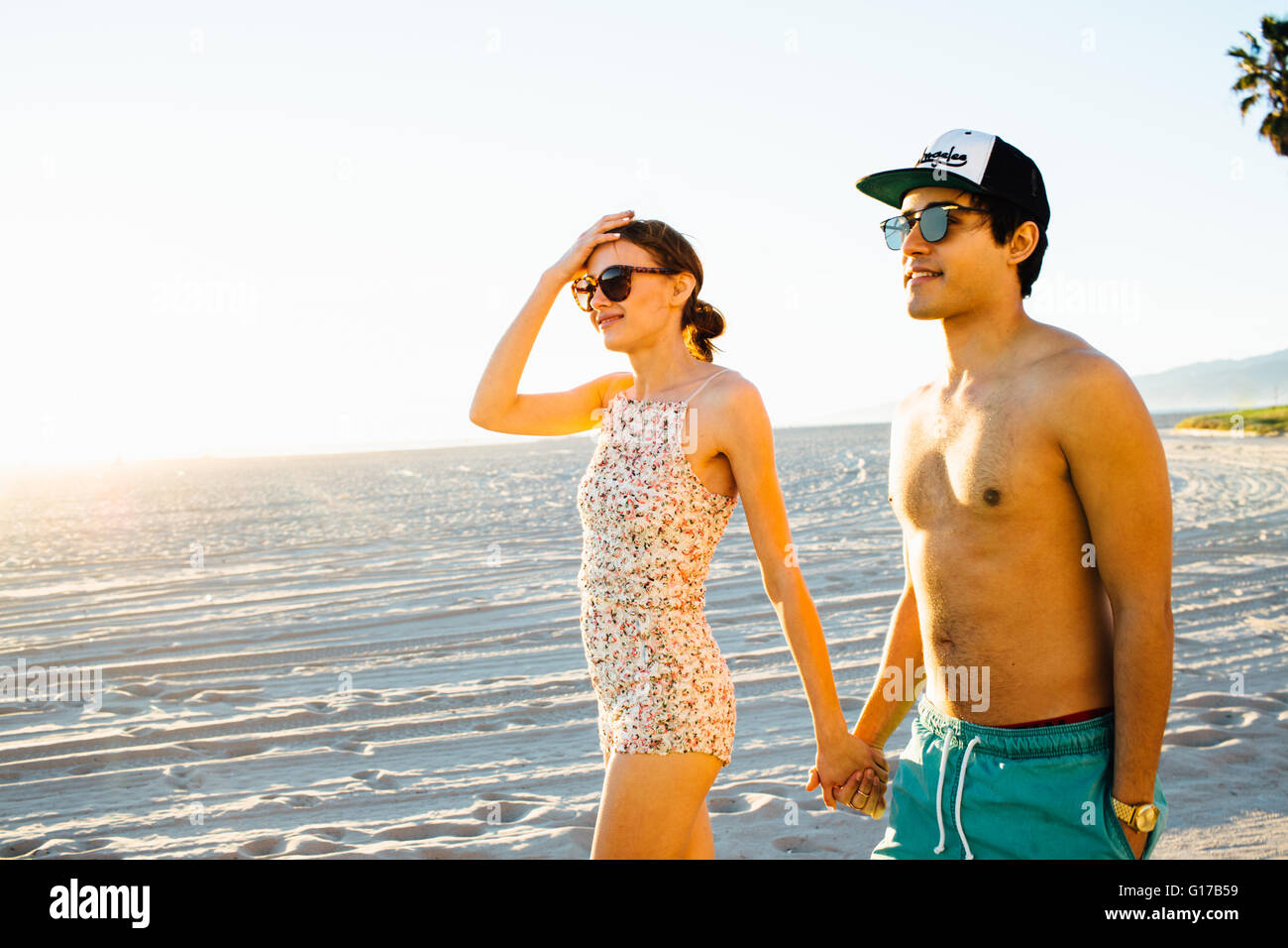 Junges Paar tragen Badehose und Shorts ein Spaziergang am Strand von Venice Beach, Kalifornien, USA Stockfoto