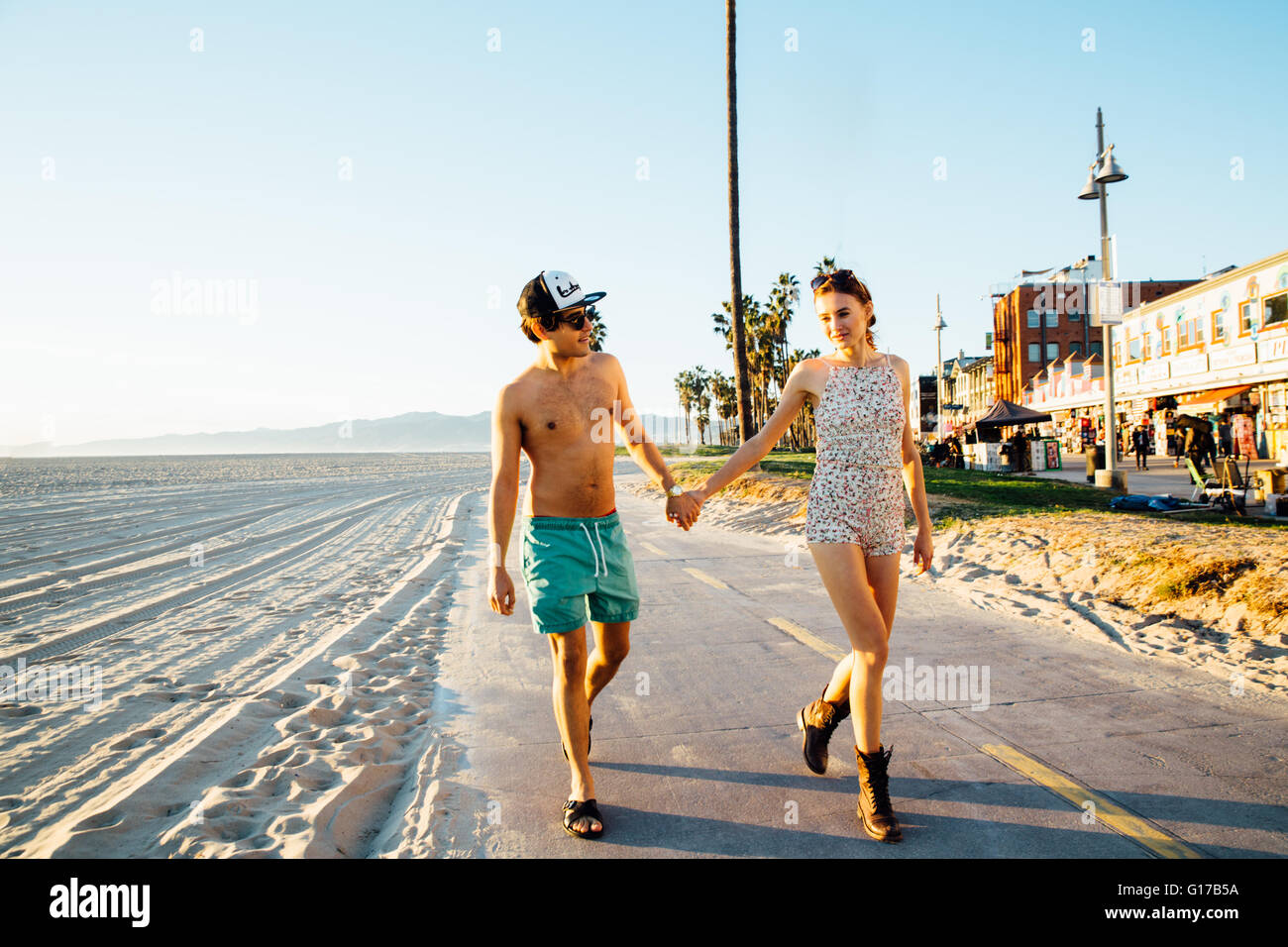 Junges Paar tragen Badehose und Shorts ein Spaziergang am Strand von Venice Beach, Kalifornien, USA Stockfoto