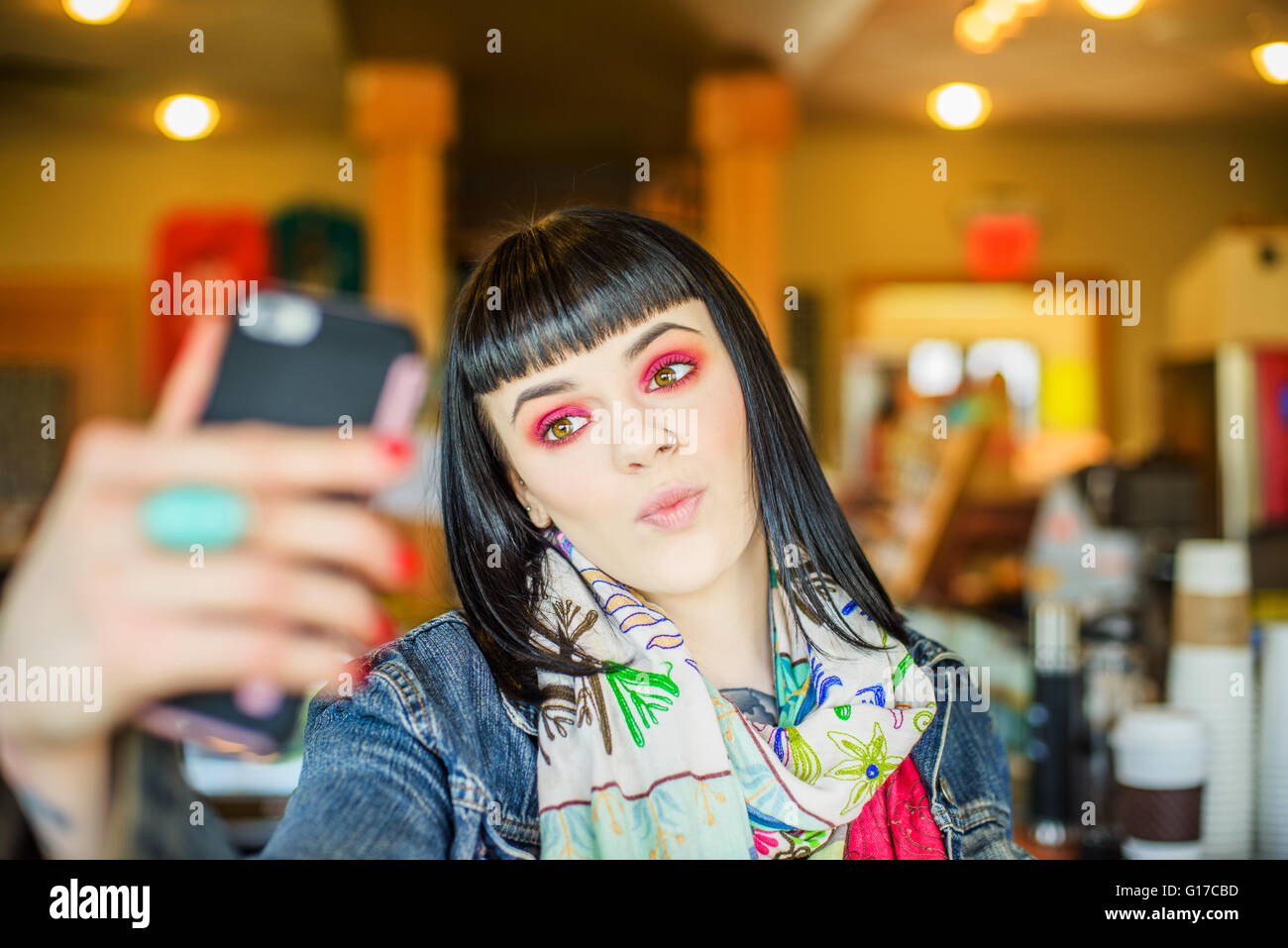 Frau mit Smartphone zu Selfie schmollend Stockfoto