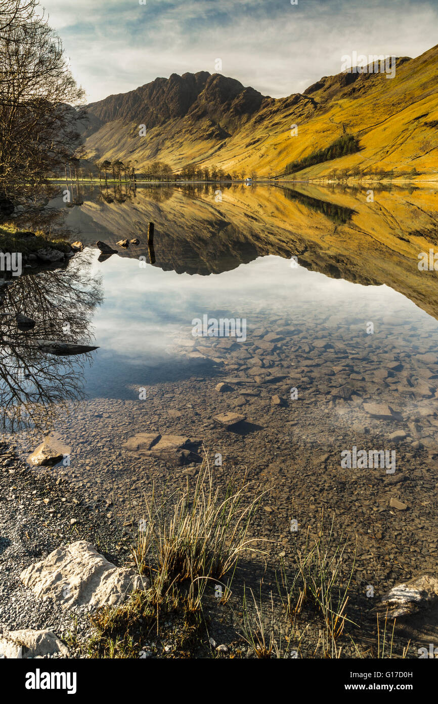 Glasartige Oberfläche von Buttermere reflektiert umgebenden Fells bald nach Sonnenaufgang Stockfoto