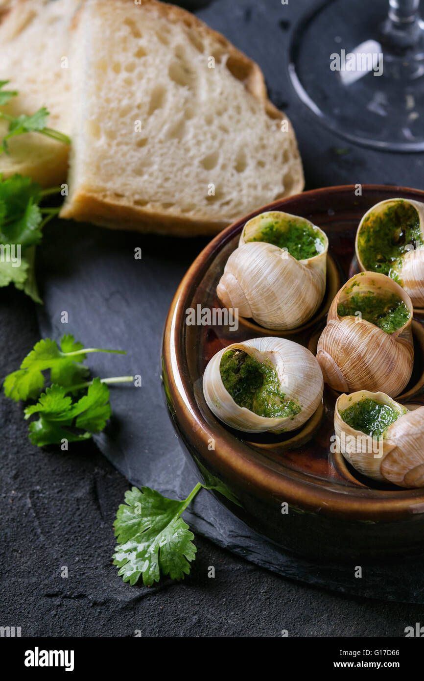 Escargots de Bourgogne - Schnecken mit Kräuter-butter, Gourmet-Gericht, in traditionellen keramischen Pfanne mit Petersilie und Brot auf Stein Lamelle Stockfoto