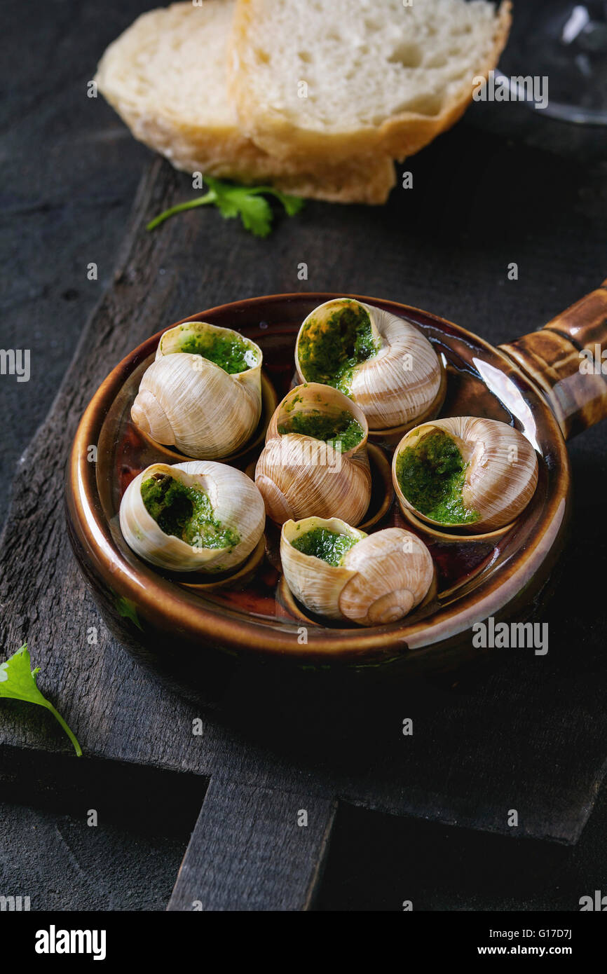 Escargots de Bourgogne - Schnecken mit Kräuter-butter, Gourmet-Gericht, in traditionellen keramischen Pfanne mit Petersilie und Brot auf hölzernen cho Stockfoto