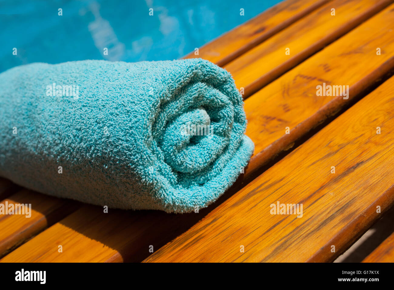türkisfarbenen Handtuch auf einer Liege am blauen Pool Stockfoto