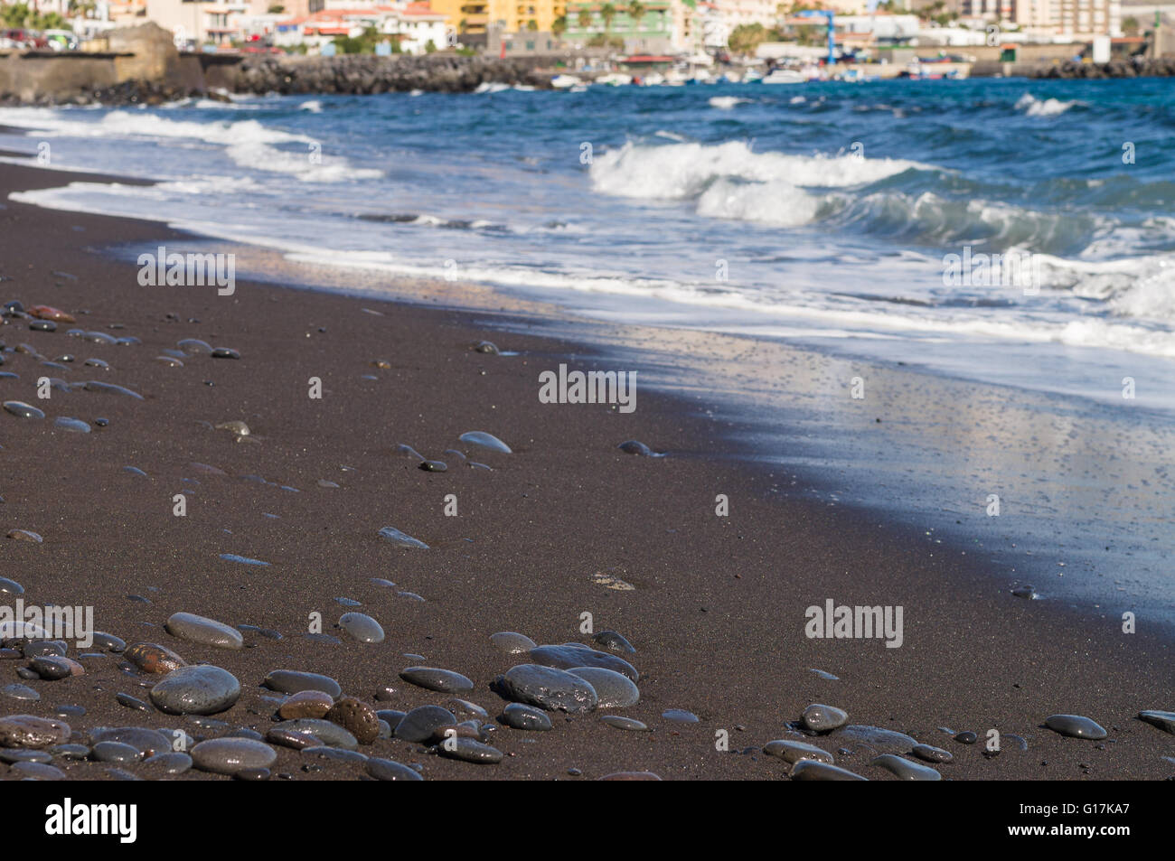 Schwarzen Sand steiniger Strand mit Meeresrauschen und Ferienort auf Hintergrund, Reisekonzept Stockfoto