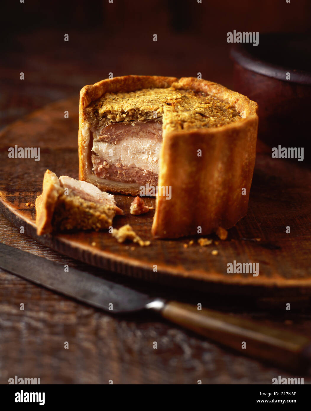 Erhöhten Huhn und Schweinefleisch Pie auf Holz Schneidebrett, close-up Stockfoto