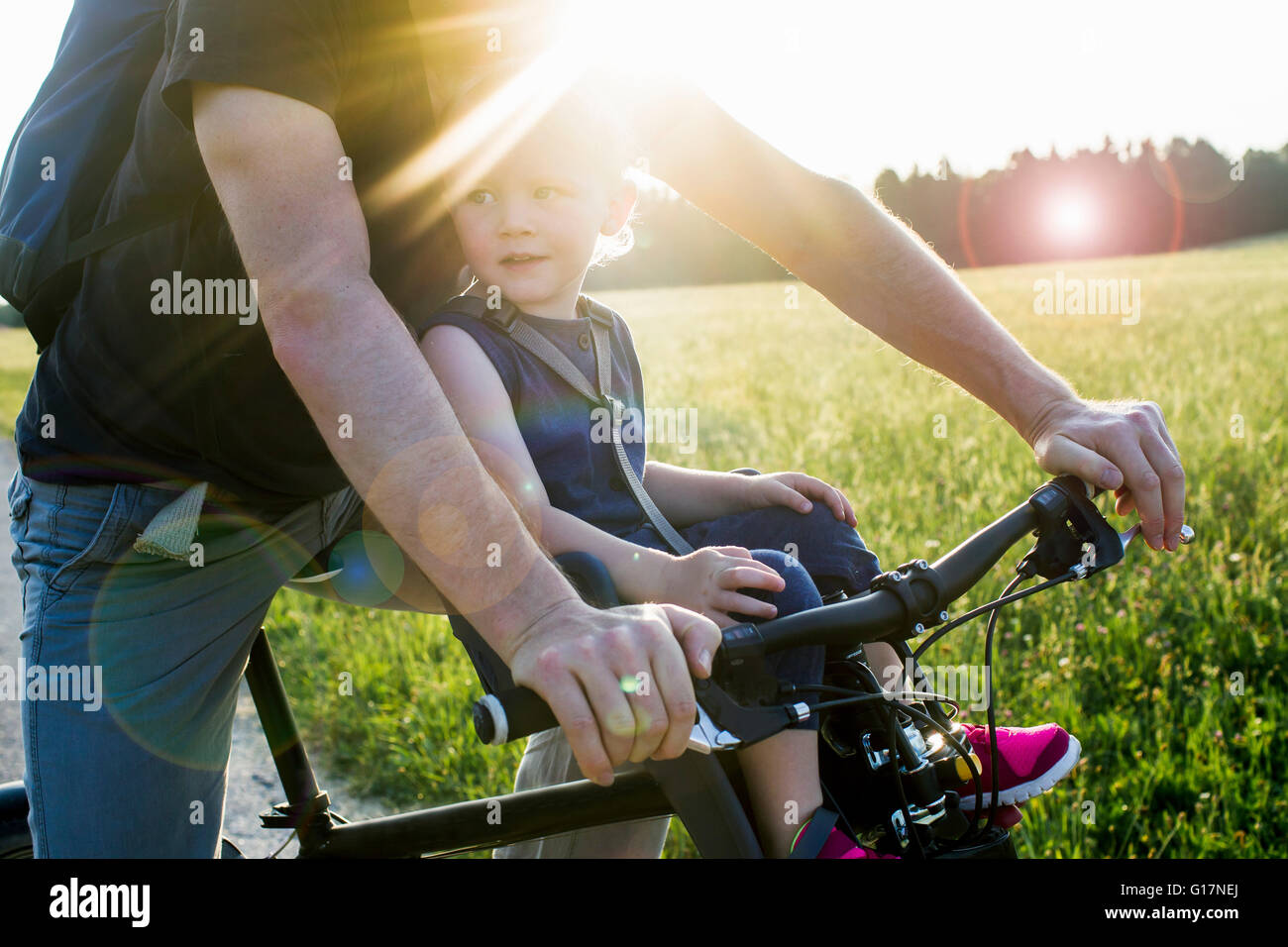 Vater und Baby Tochter reiten Bike zusammen, Mittelteil Stockfoto