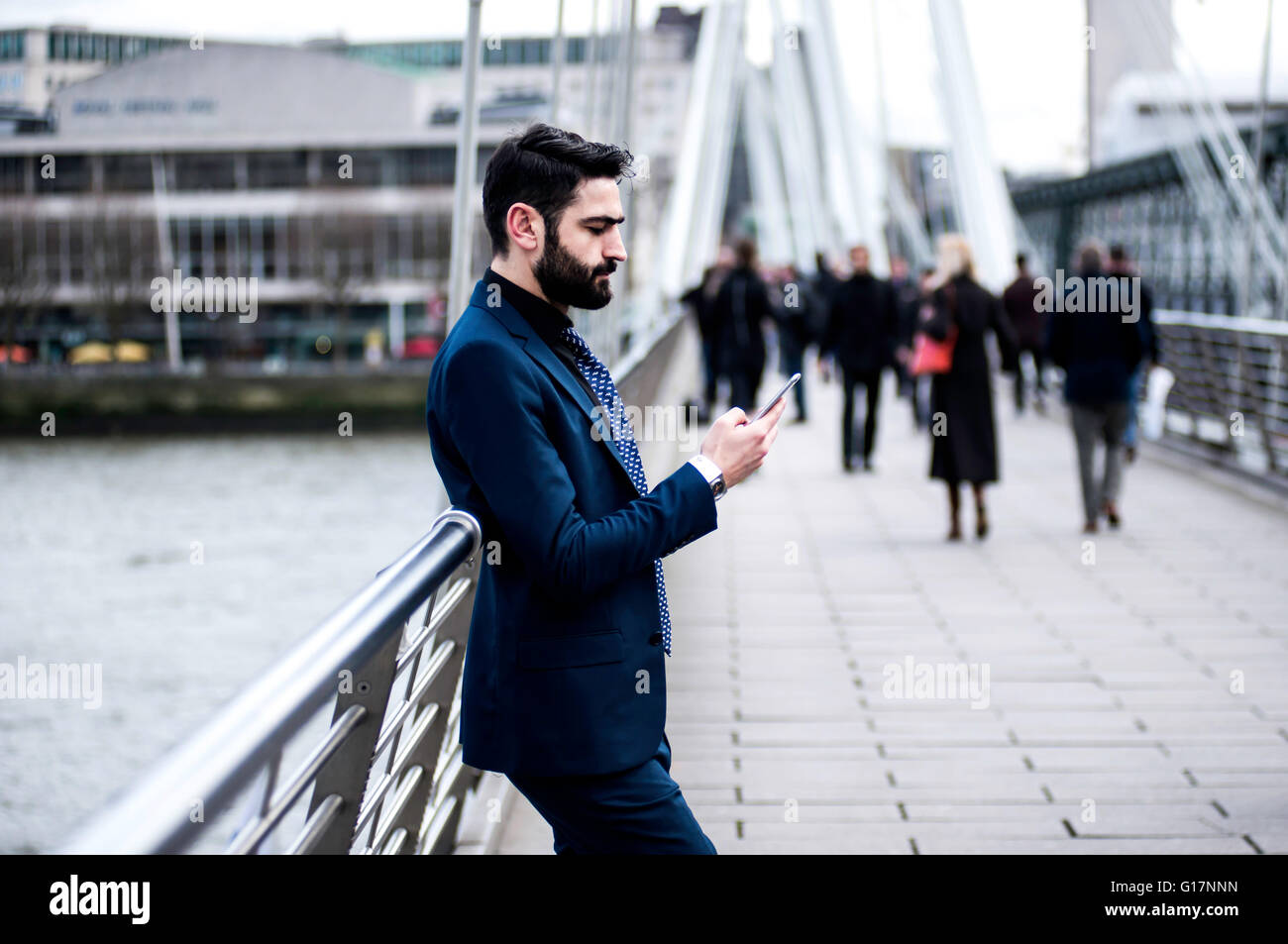 Geschäftsmann gelehnt Fußgängerbrücke Geländer lesen Smartphone Text, London, UK Stockfoto