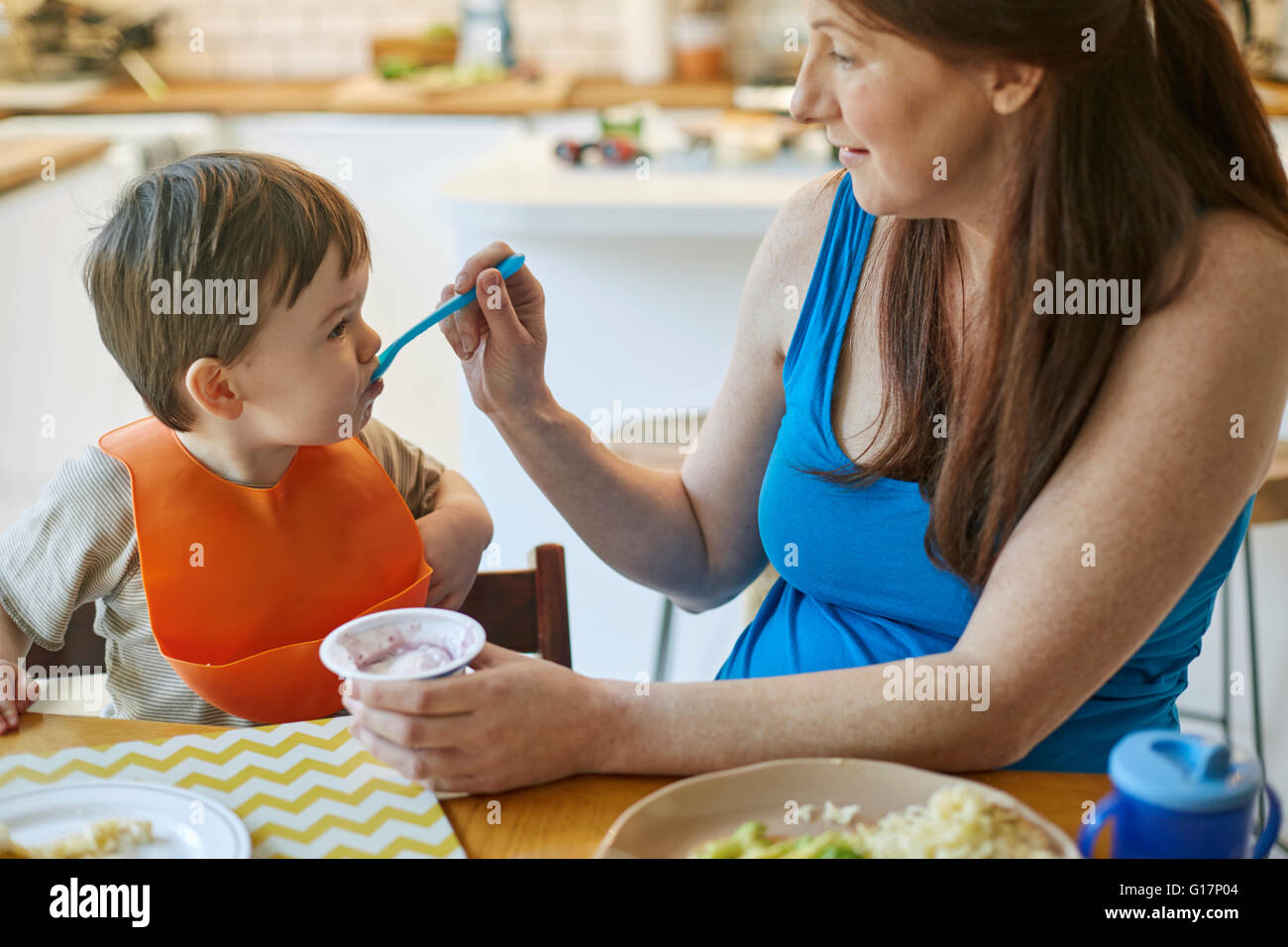 Frau, Fütterung Baby Sohn am Tisch Stockfoto